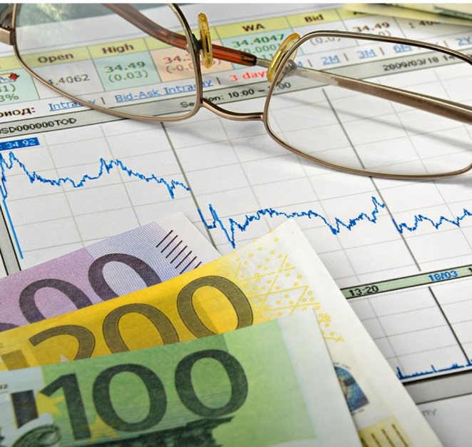Euro banknotes and reading glasses on a financial chart